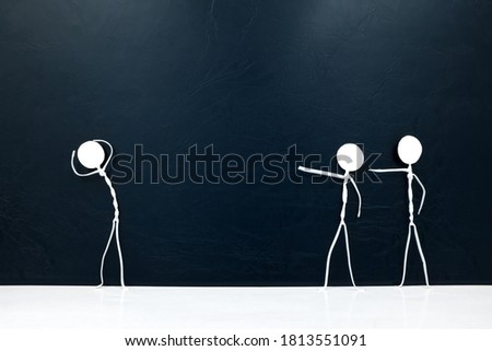 People figures pointing fingers on a scared stick man  on a dark background. Bullying, victim blaming, accusation and abuse concept. Royalty-Free Stock Photo #1813551091