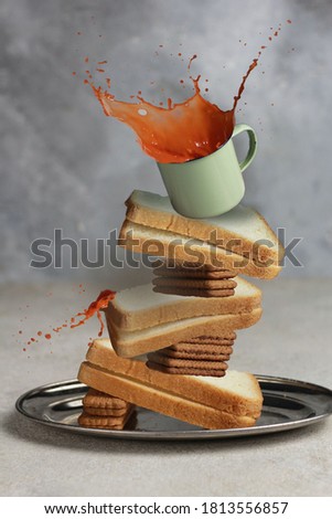Bread, biscuits and a glass of drink spilled in one frame