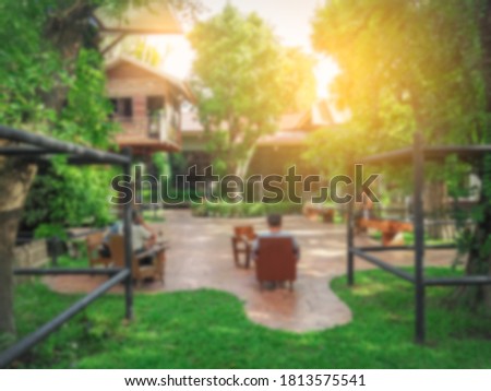The photo is blurred from the back of many people sitting in the garden.