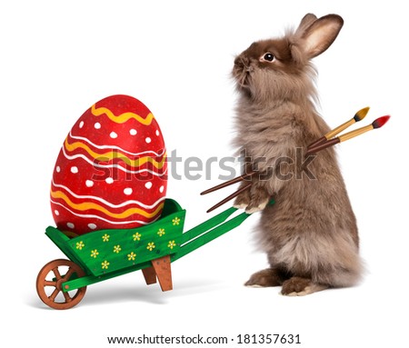 Cute Easter bunny rabbit with a little green wheelbarrow and a red painted Easter egg, isolated on white, CG and photo