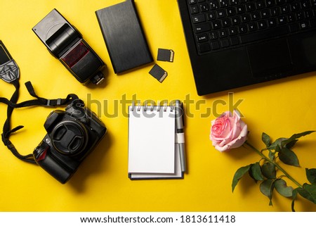 cell phone, flash, camera, notebook, memory card, notepad and rose on yellow background