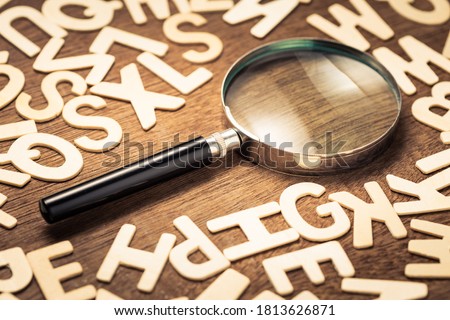 Magnifying glass with many wood letters of English alphabets, searching words to communicate, learning English concept Royalty-Free Stock Photo #1813626871