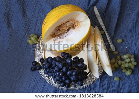 Ripe melon and grapes bunch on a silver tray top view