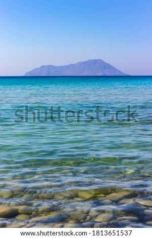 Distant island on horizon under blue sky and clear sea water