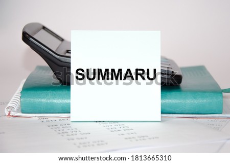 word summaru written on a block of paper on the background of a calculator and notepad close-up. High quality photo