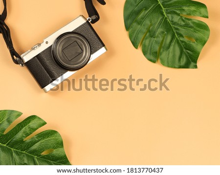 Top view or flat lay of vintage camera on orange background with monstera leaves decoration. Freelance, creative , hobby concept.