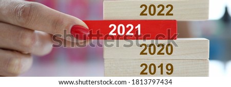 Female hand hold red wooden block with 2021 sign closeup. Chops and changes concept