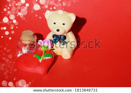 Bear sits on a red background, near a heart
