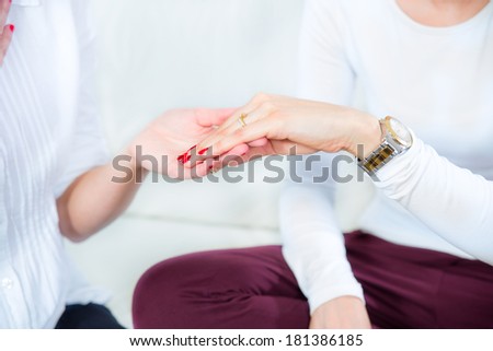 Women looking at engagement ring on the finger of one of them