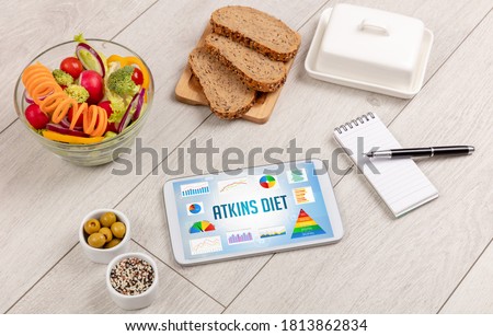 Organic food and tablet pc showing ATKINS DIET inscription, healthy nutrition composition