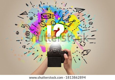 Close-up of a hand holding digital camera with abstract drawing and !? inscription