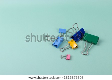a group of vivid color office metal paper clips for paper on the pale pink mono colour background. minimalism style, top view shot.