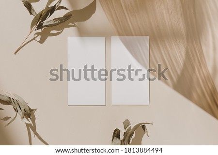 Blank paper sheet cards with mockup copy space, wooden tray and dry leaves with sunlight shadow on beige background. Minimal business brand template. Flat lay, top view