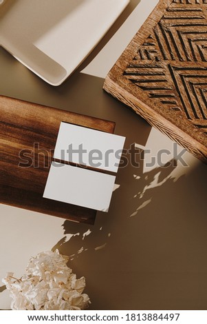 Blank paper sheet cards with empty copy space, wooden tray, casket and dry flowers with sunlight shadows on beige background. Flat lay, top view business mock up template.
