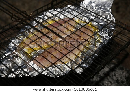Fish fillets in foil being cooked using a braai grid and hot coals. South African food concept photo.  This photo has selective focus. 