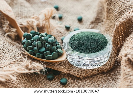 Spirulina chlorella tablets on a spoon, powder in a glass bowl. Super food for a healthy diet, vitamins, minerals, trace elements for health and beauty Royalty-Free Stock Photo #1813890047