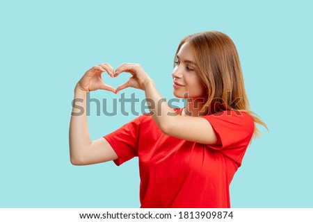 Appreciation sign. Love affection. Portrait of supportive kind woman in red t-shirt showing heart gesture isolated on blue background. Romantic message.