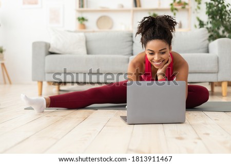 Online Training. Fit Black Woman Exercising Stretching At Laptop Computer Watching Fitness Video At Home