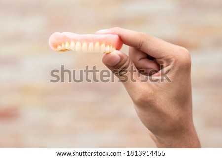 A man is holding dentures in his hands. Removable dentures flexible. False teeth.