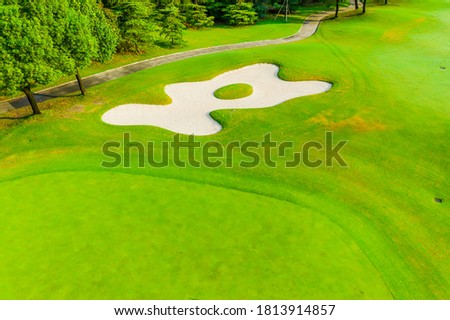 Aerial view of green grass and sand trap on golf course.