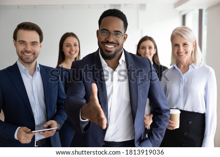 Portrait of smiling African American team leader stretch hand greeting job candidate or applicant in office. Happy multiracial businesspeople meet welcome newcomer at workplace. Employment concept. Royalty-Free Stock Photo #1813919036