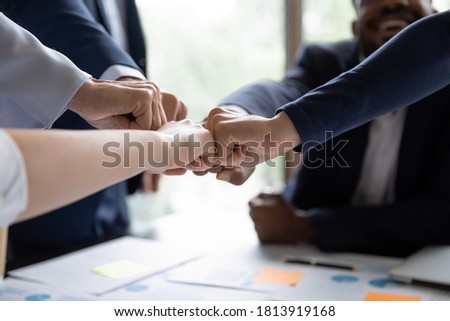 Crop close up of multiracial businesspeople give fists bump participate in teambuilding activity at meeting. Motivated diverse colleagues join hands take part in training, show motivation for success. Royalty-Free Stock Photo #1813919168
