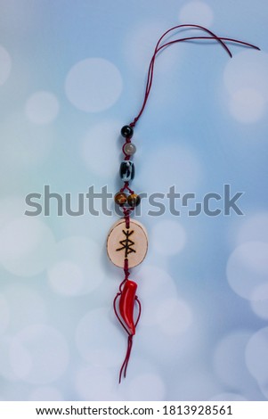 Magic runes amulet. Amulet on a blue background with pink roses and coral stone