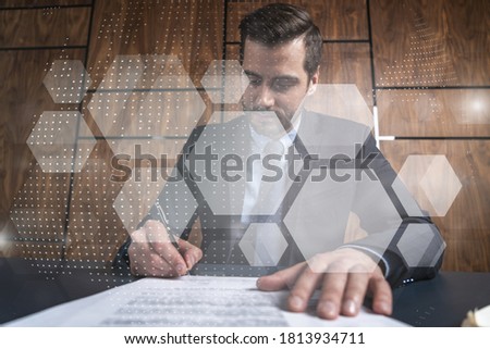 Businessman in office signs contract and abstract technology hologram. Double exposure. Formal wear.