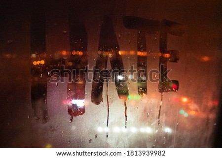 Hate, negative emotions. Inscription on the fogged glass, night city on the background. image with tinting and noise effect