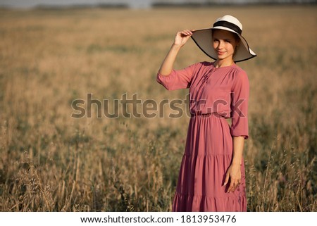 beautiful young woman in hat in summer field