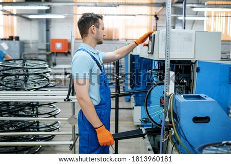 Man at machine tool checks bicycle rim, factory