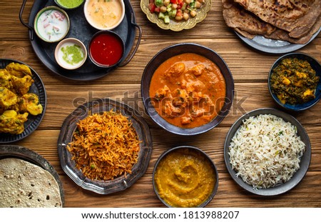 Assorted Indian home food, different dishes and snacks on wooden rustic table. Homemade Pilaf, butter chicken curry, palak paneer, chicken tikka, dal soup, naan bread, choice of chutney. Top view
 Royalty-Free Stock Photo #1813988207