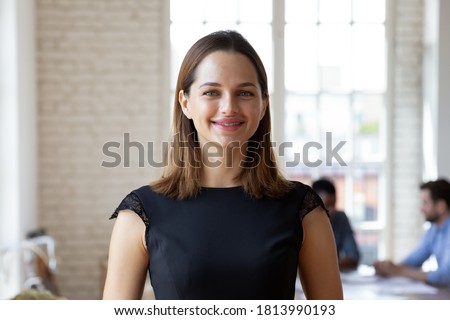 Headshot portrait of smiling millennial businesswoman stand forefront in office look at camera posing, happy confident young Caucasian female employee or company boss CEO show confidence in boardroom Royalty-Free Stock Photo #1813990193