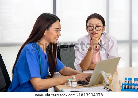 Two Asian female medical doctor sitting at desk and meeting discussion about vaccine with laptop computer