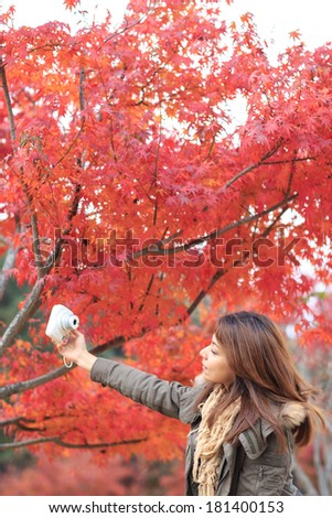 Autumn outdoor portrait of beautiful asia young woman holding a camera.