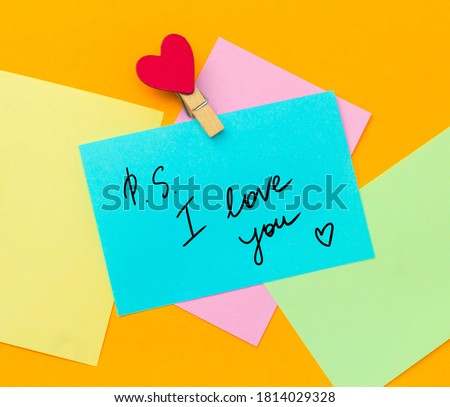 multicolored paper notes with text ps i love you  with cloth pin decorated with red heart 
 on a vibrant yellow background
