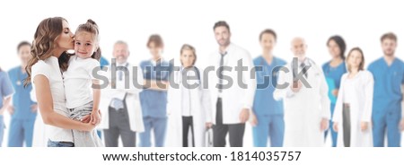 Mother kisses her daughter, team of doctors in medical clinic on background isolated on white