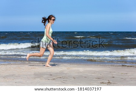 Teenage girl running, jumping on beach 