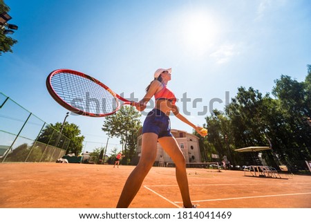 Young athletic woman playing tennis on the court.