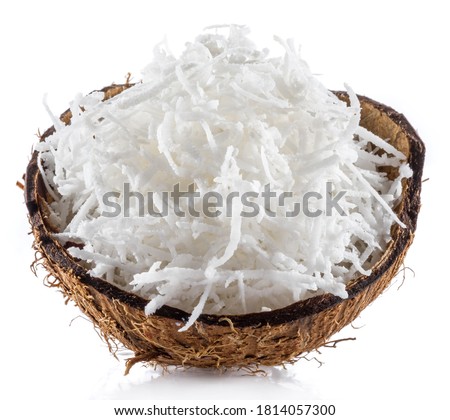 Shredded coconut flakes in the piece of coconut shell isolated on white background. Close-up. Royalty-Free Stock Photo #1814057300