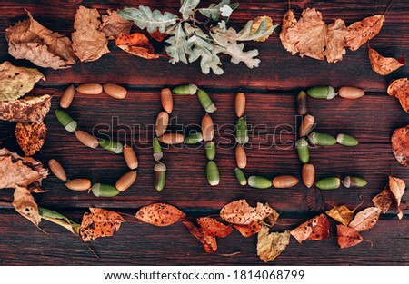 Lettering SALE made up of autumn leaves and acorns. Discounts and sales, lettering on a wooden background. Advertising picture for seasonal discounts, creative concept for stores