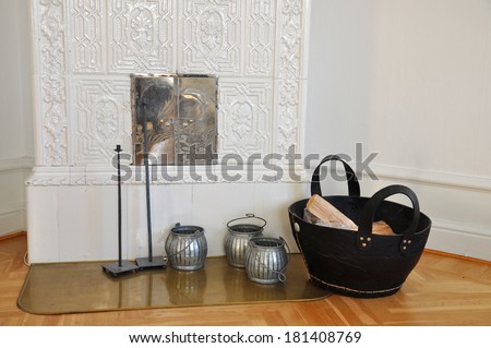 Old fashioned tiled stove with wood in a basket in the living room. Royalty-Free Stock Photo #181408769