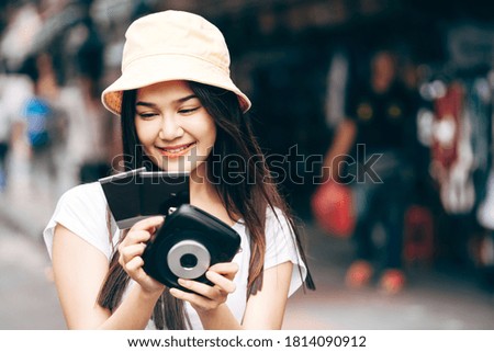 Young adult asian traveller happy woman in white shirt with backpack solo journey concept. Holding instant camera film photo. Outdoor on day background with copy space.