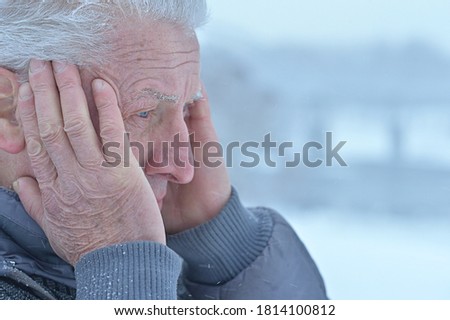 Portrait of sad senior man standing outdoors in winter