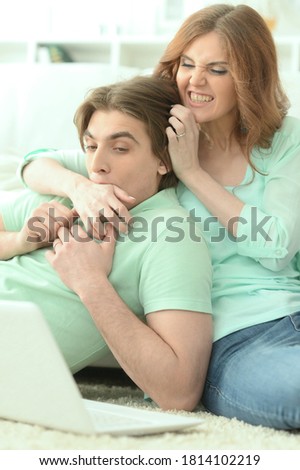 Portrait of happy young couple looking at laptop while lying on floor