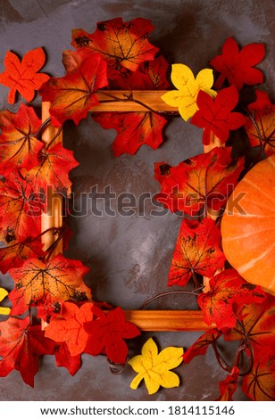 Autumn background with the picture frame and decorative fallen leaves shaping the copy space against the grey background