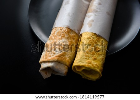 Flour tortilla with filling on a platter. Fast food photo subject on a black background.