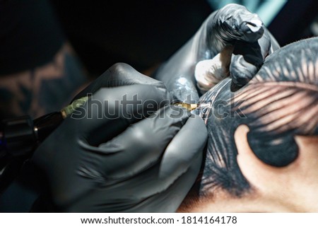 Picture of master doing black tattoo of snake for woman
