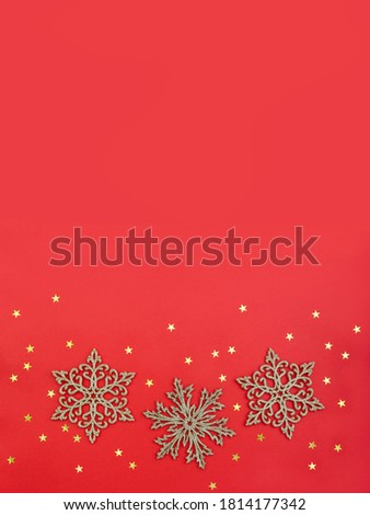 Christmas pattern of glitter snowflakes and gold starry confetti on red background. Vertical postcard. Place for your text.