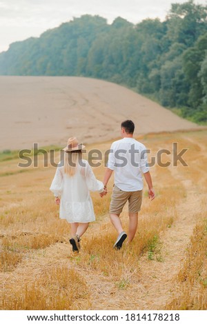 Image of couple holding by hands and walking along the field